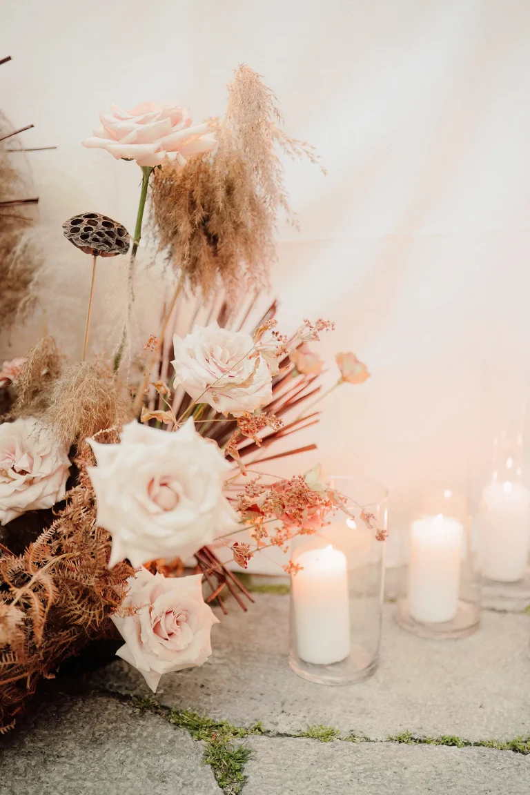 Un elegante composizione floreale con accanto delle candele bianche