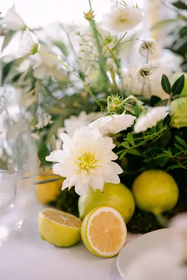 Un grazioso centro tavola caratterizzato da fiori bianchi e limoni